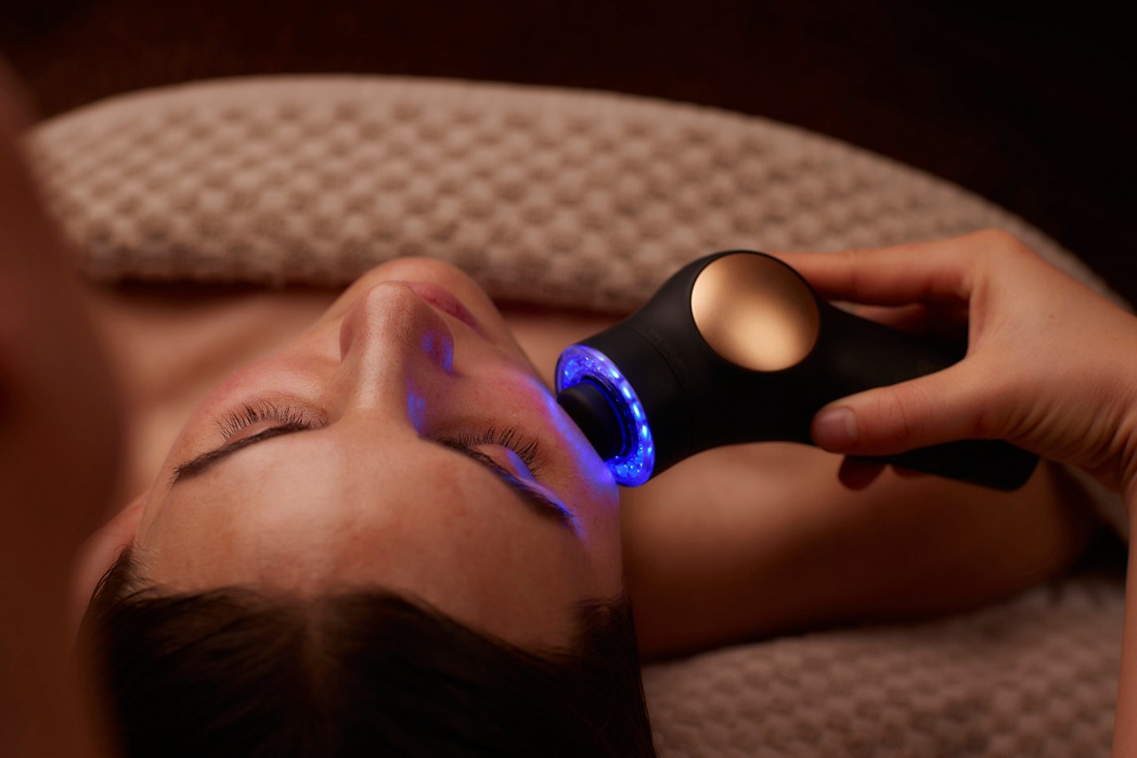 Spa therapist giving a woman a Theraface microcurrent facial treatment.